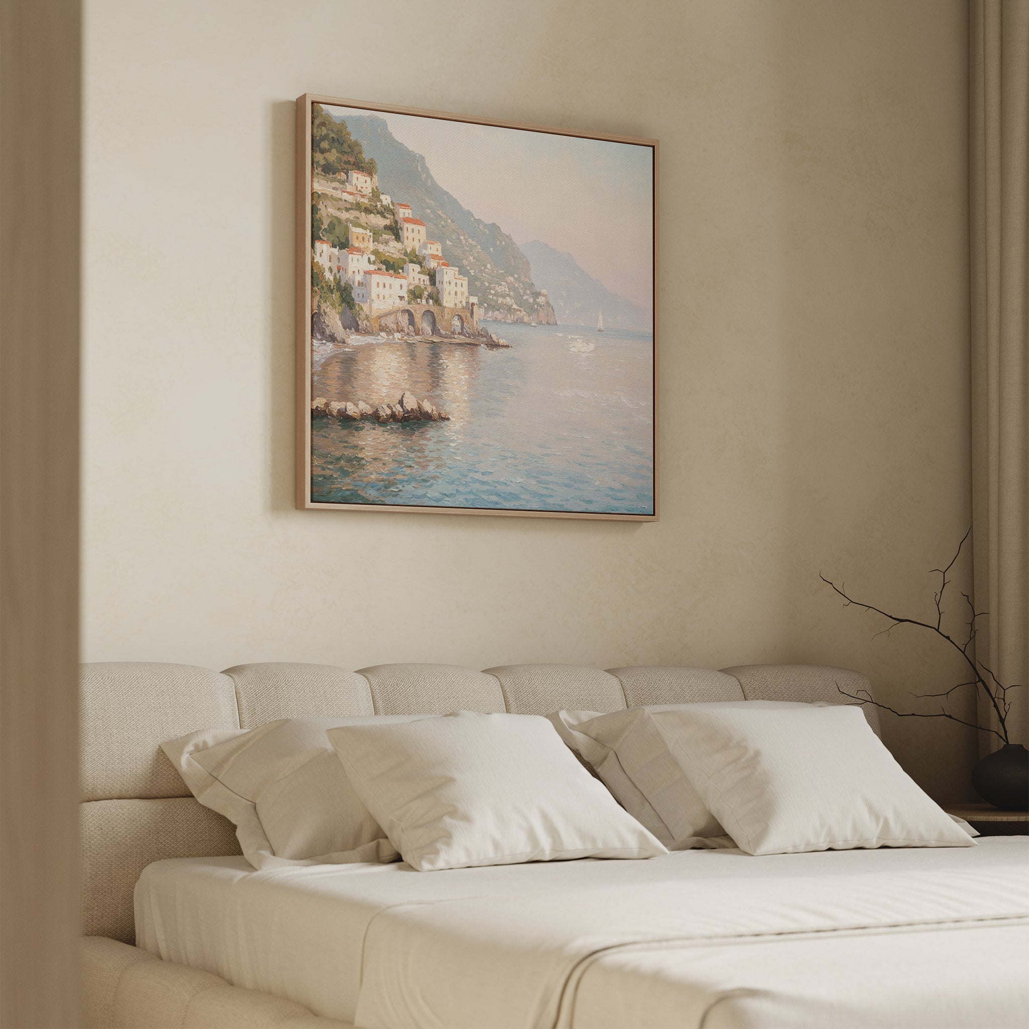 A minimal, modern bedroom features a beige bed, white pillows, and the Mediterranean Dreams Canvas Art - Square of a coastal village above the headboard. Soft natural light filters through a curtain on the right, enhancing the serene home decor.