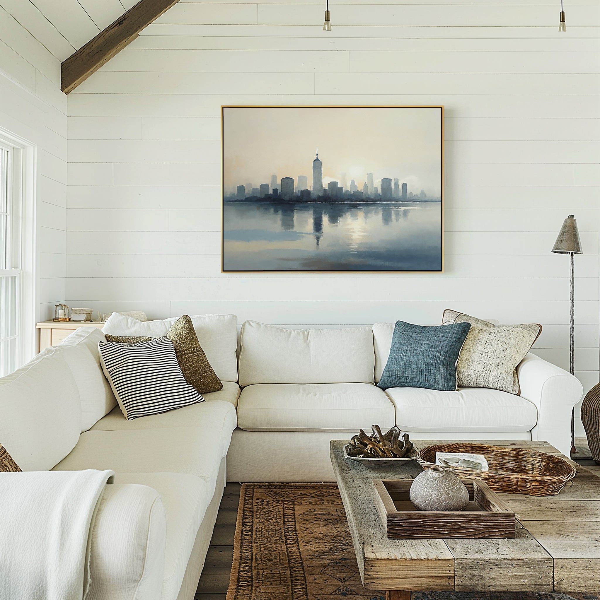A bright, airy living room with white shiplap walls, a large white sectional sofa with assorted pillows, a rustic wooden coffee table, and the Metropolitan Dawn Canvas Art - Horizontal above the couch. Natural light fills the space.