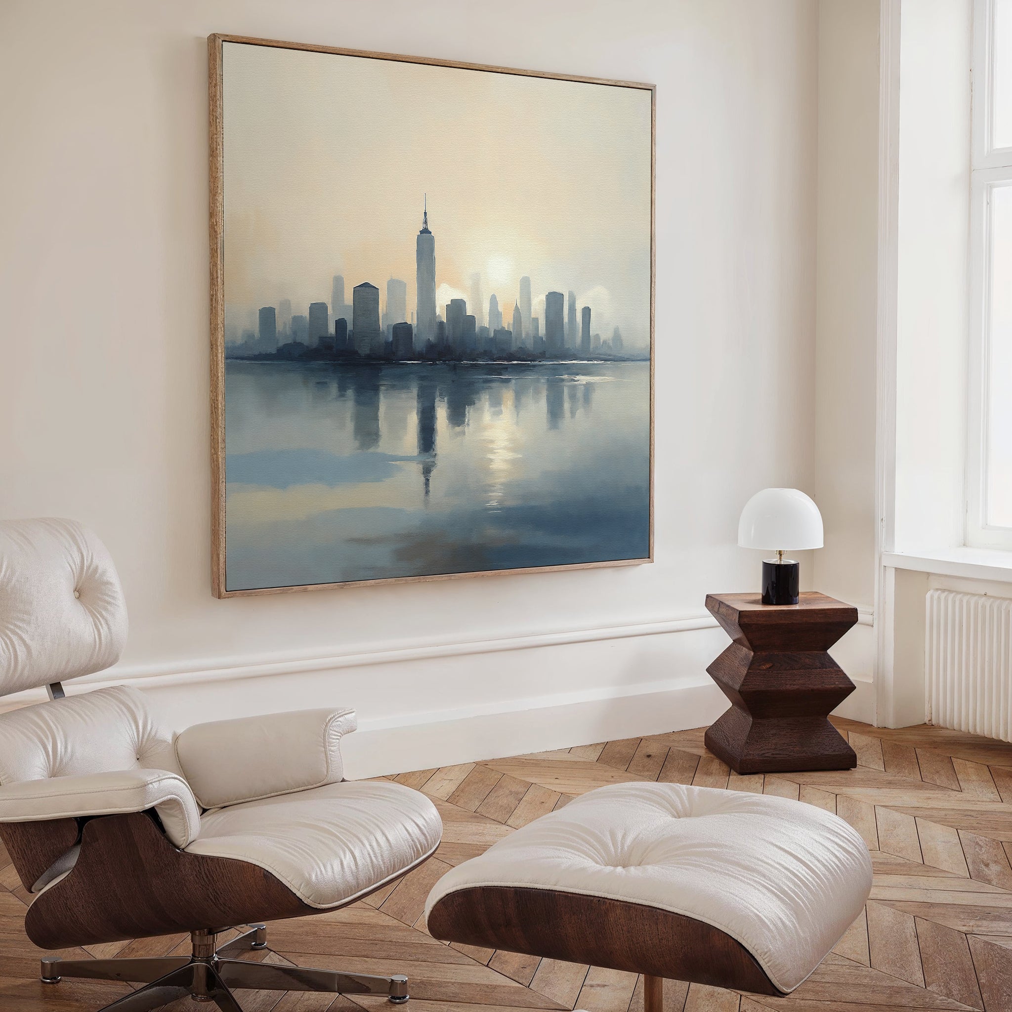 A modern living room with a white leather lounge chair and ottoman, wooden side table with lamp, and the Metropolitan Dawn Canvas Art - Square featuring a vivid city skyline over water. Light pours in from tall windows, emphasizing the elegant urban vibe.