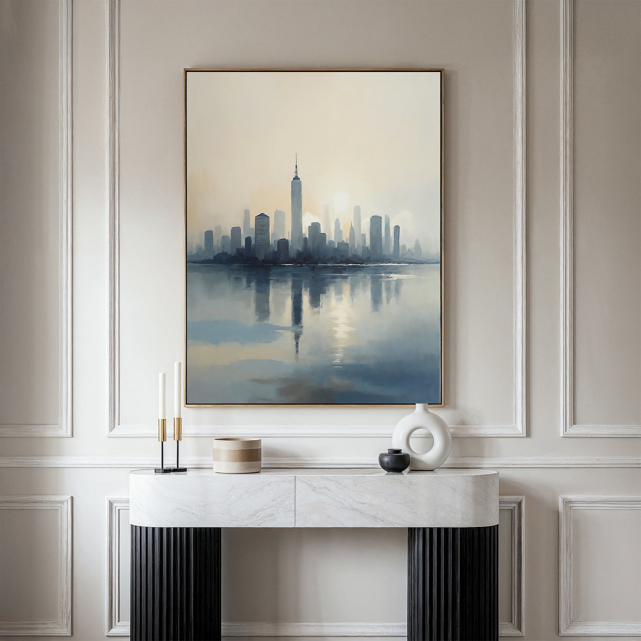 A modern entryway features a marble console table with minimalist decor beneath the Metropolitan Dawn Canvas Art - Vertical, showcasing a soft city skyline, all set against elegant paneled walls.