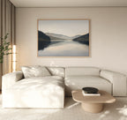 A modern living room with a light beige sectional, round wood coffee table, potted plant, and the Mirror Valley Canvas Art - Horizontal enhances the calm natural palette and minimalist decor.