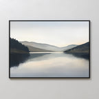 The Mirror Valley Canvas Art - Horizontal features a tranquil landscape with a serene lake reflecting distant hills and a misty sky, in calming natural tones and soft brushwork, displayed on a light-colored wall.
