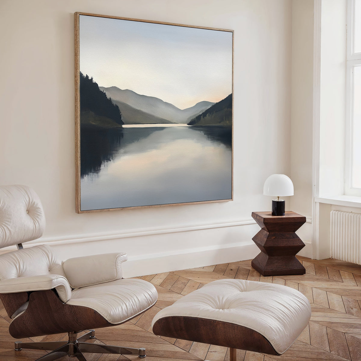A modern, minimalist room with a white leather lounge chair and ottoman, a small wooden side table with a white lamp, and the Mirror Valley Canvas Art - Square as stunning wall decor.