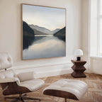 A modern, minimalist room with a white leather lounge chair and ottoman, a small wooden side table with a white lamp, and the Mirror Valley Canvas Art - Square as stunning wall decor.