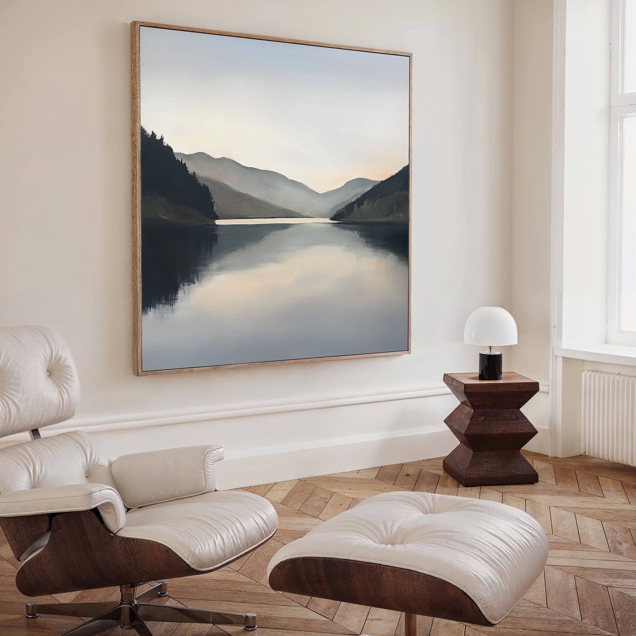 A modern, minimalist room with a white leather lounge chair and ottoman, a small wooden side table with a white lamp, and the Mirror Valley Canvas Art - Square as stunning wall decor.