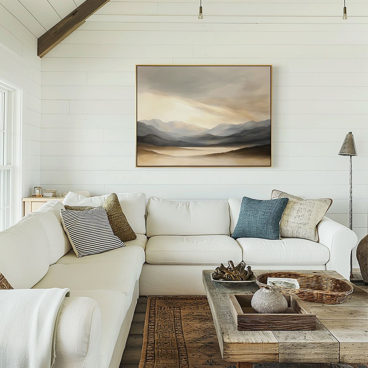 A cozy living room features a white sectional, patterned pillows, a rustic wood coffee table, and the Mountain Reverie Canvas Art - Horizontal on a white shiplap wall. Warm neutrals define the Nordic Park-inspired decor.
