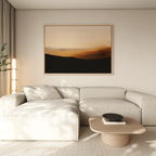 A modern living room features a beige sectional sofa, light wood coffee table, and the Sienna Ridge Canvas Art in warm tones on the wall. Soft natural light through sheer curtains enhances the contemporary decor.