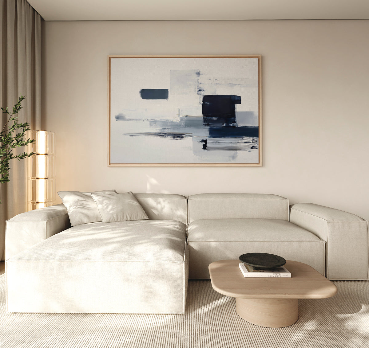 A modern living room features a cream sectional sofa, light wood coffee table, and the Navy Brushwork Canvas Art - Horizontal above. A tall plant in the corner and ample natural light complete the inviting space.