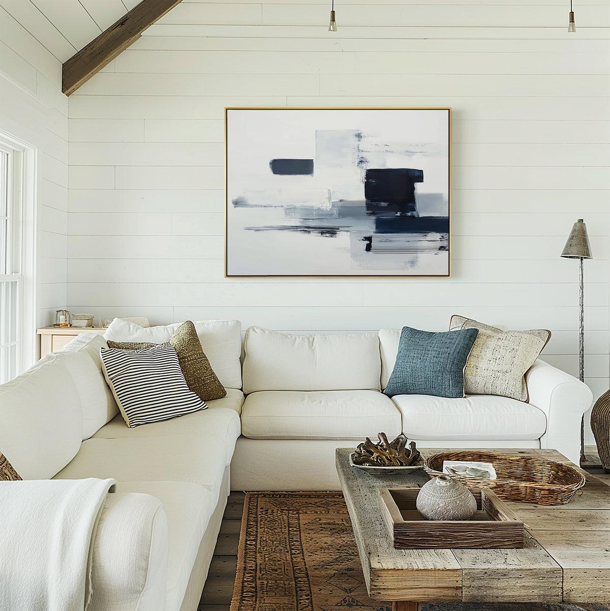 A cozy living room features a white sectional sofa with assorted cushions, a rustic wooden coffee table topped with decor, and the Navy Brushwork Canvas Art - Horizontal as striking wall art on a shiplap backdrop.