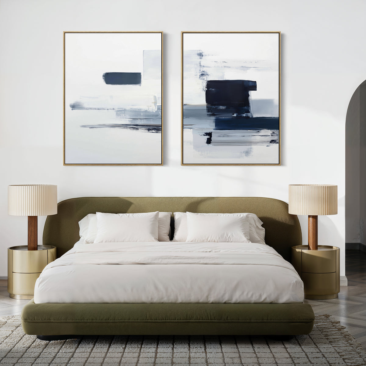 A modern bedroom features a low olive-green bed with white bedding, two beige nightstands with matching lamps, and the Navy Brushwork - Set Of 2 above the headboard for a stylish touch of minimalist decor.