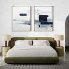 A modern bedroom features a low olive-green bed with white bedding, two beige nightstands with matching lamps, and the Navy Brushwork - Set Of 2 above the headboard for a stylish touch of minimalist decor.