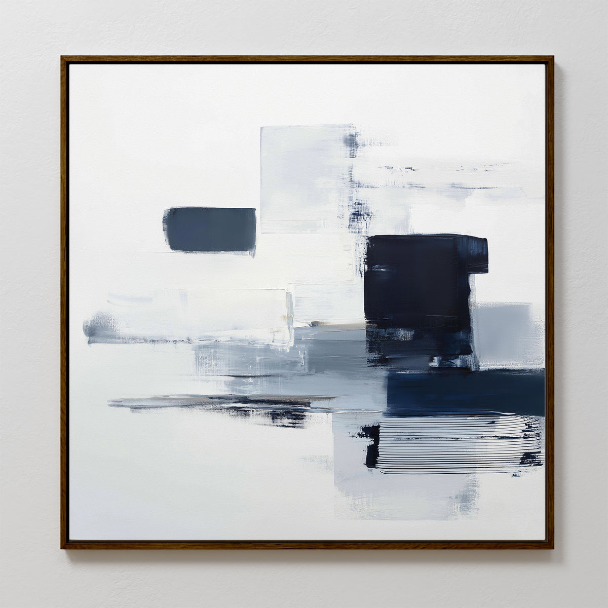 The Navy Brushwork Canvas Art - Square features abstract rectangular blocks and brushstrokes in white, gray, and navy blue with a thin brown wooden frame—perfect minimalist decor for a white wall.
