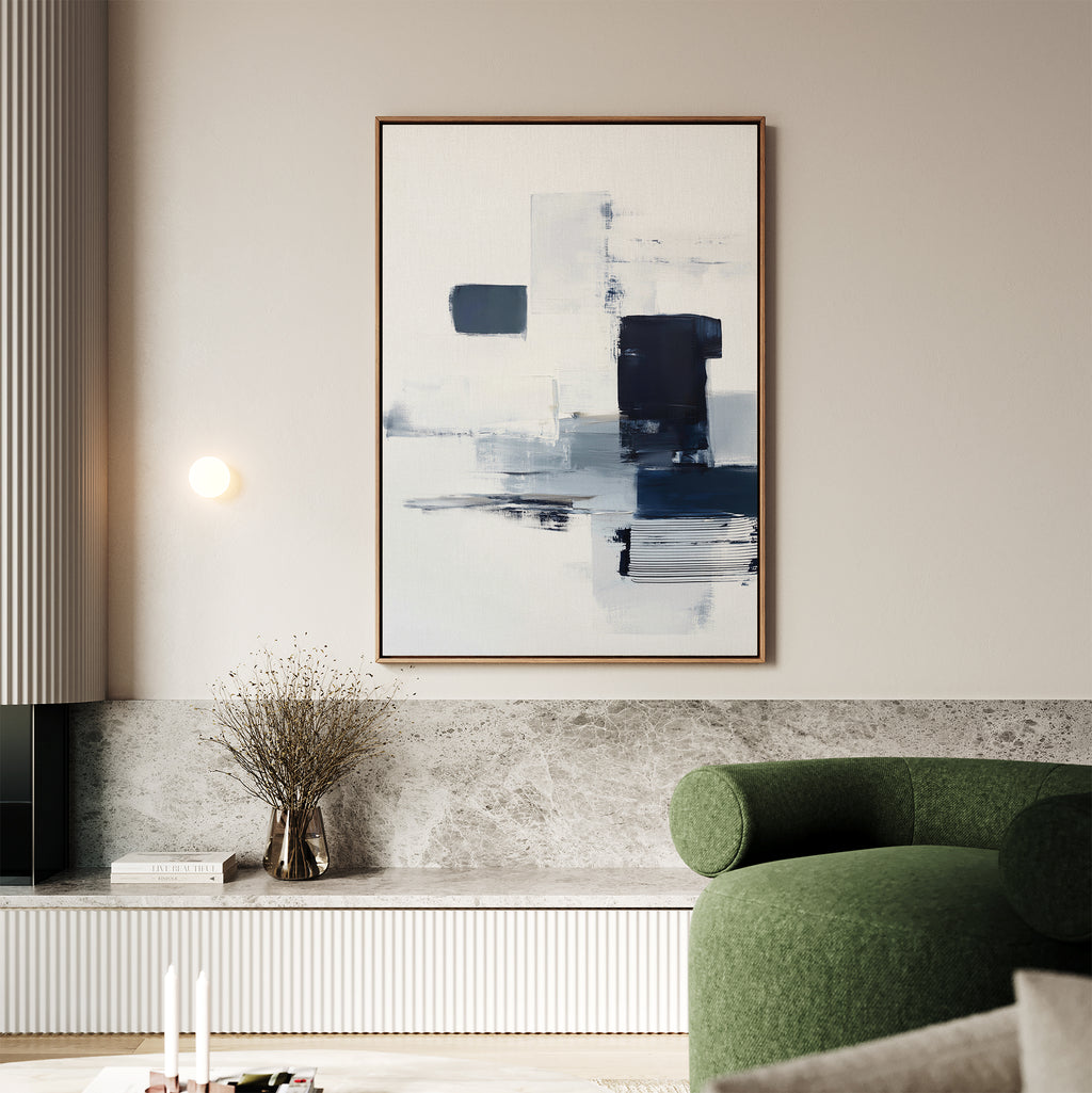 A modern living room featuring a green curved sofa, a marble ledge, dried flowers in a vase, and the Navy Brushwork Canvas Art - Vertical in blue, black, and white tones hanging on a light beige wall above.