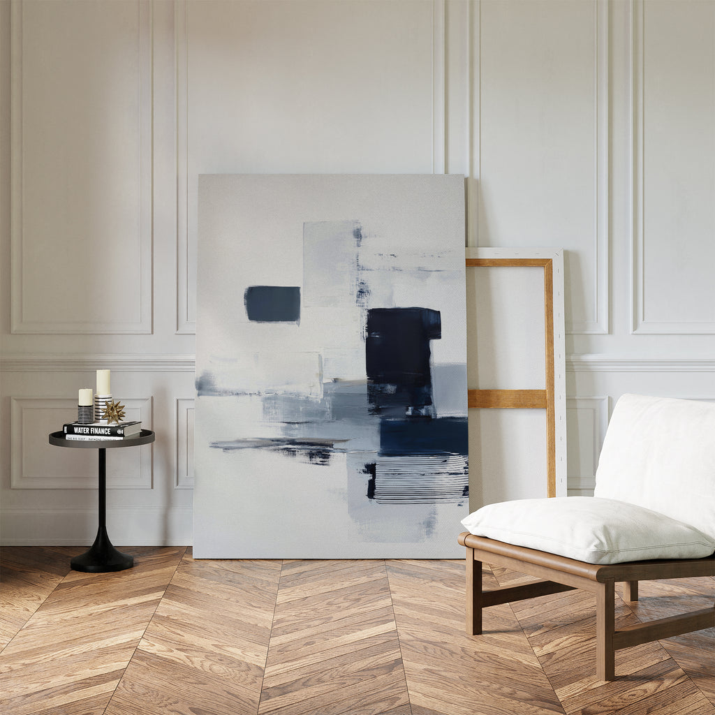 A minimalist room with herringbone wood floors features the Navy Brushwork Canvas Art - Vertical leaning against a white paneled wall, next to a modern chair and small black side table—a perfect accent for minimalist home decor.