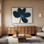 A modern living room with a wooden credenza, minimalist decor featuring the Navy Clover Canvas Art - Horizontal above it, a light wood coffee table, a vase with flowers, a beige rug, and a light sofa. Warm lighting and neutral tones complete the space.