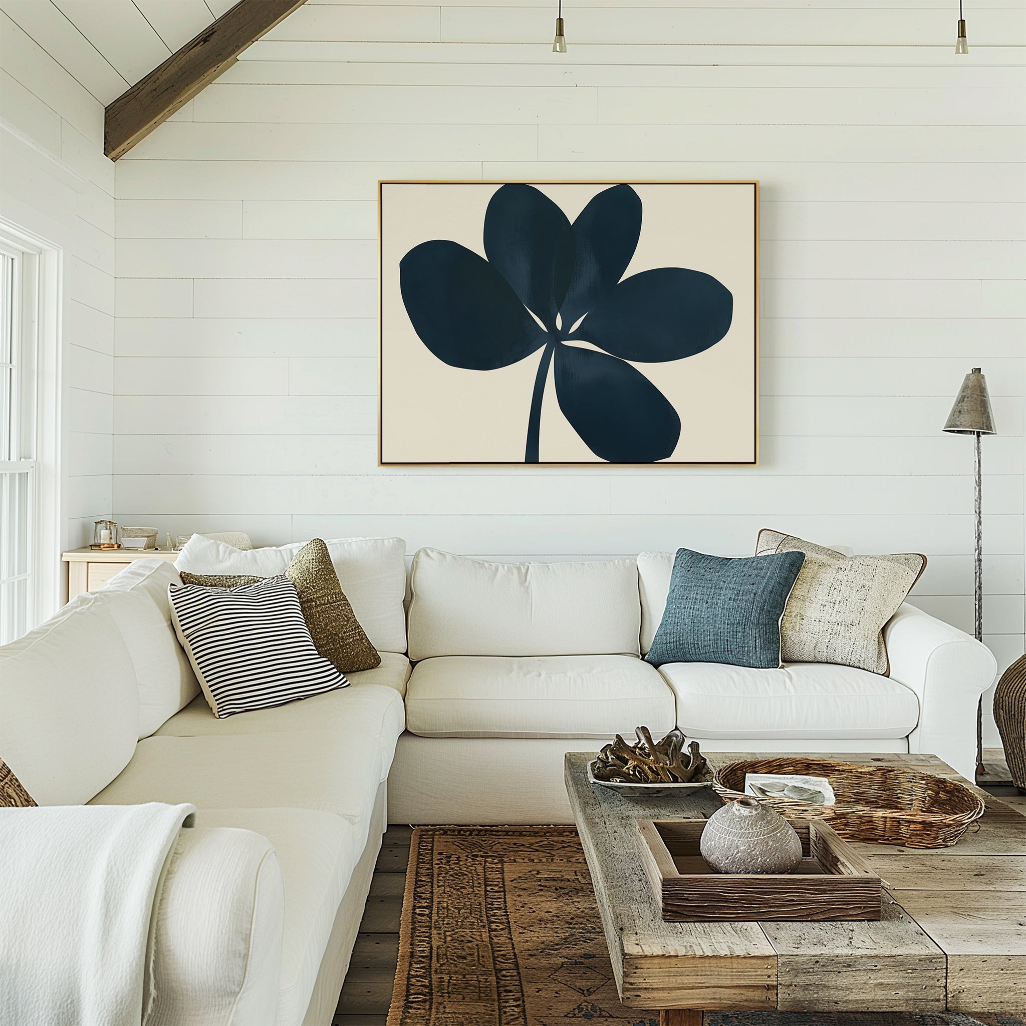 A cozy living room with a white sectional, assorted pillows, a wooden coffee table with decor, and the Navy Clover Canvas Art - Horizontal on a shiplap wall. Natural light fills the space.