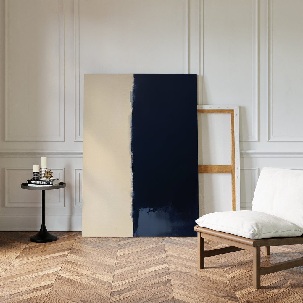 A modern room with herringbone wood floors, a white cushioned chair, a small black side table with candles and books, and the Navy Division Canvas Art - Vertical leaning against a white paneled wall creates an air of modern elegance.