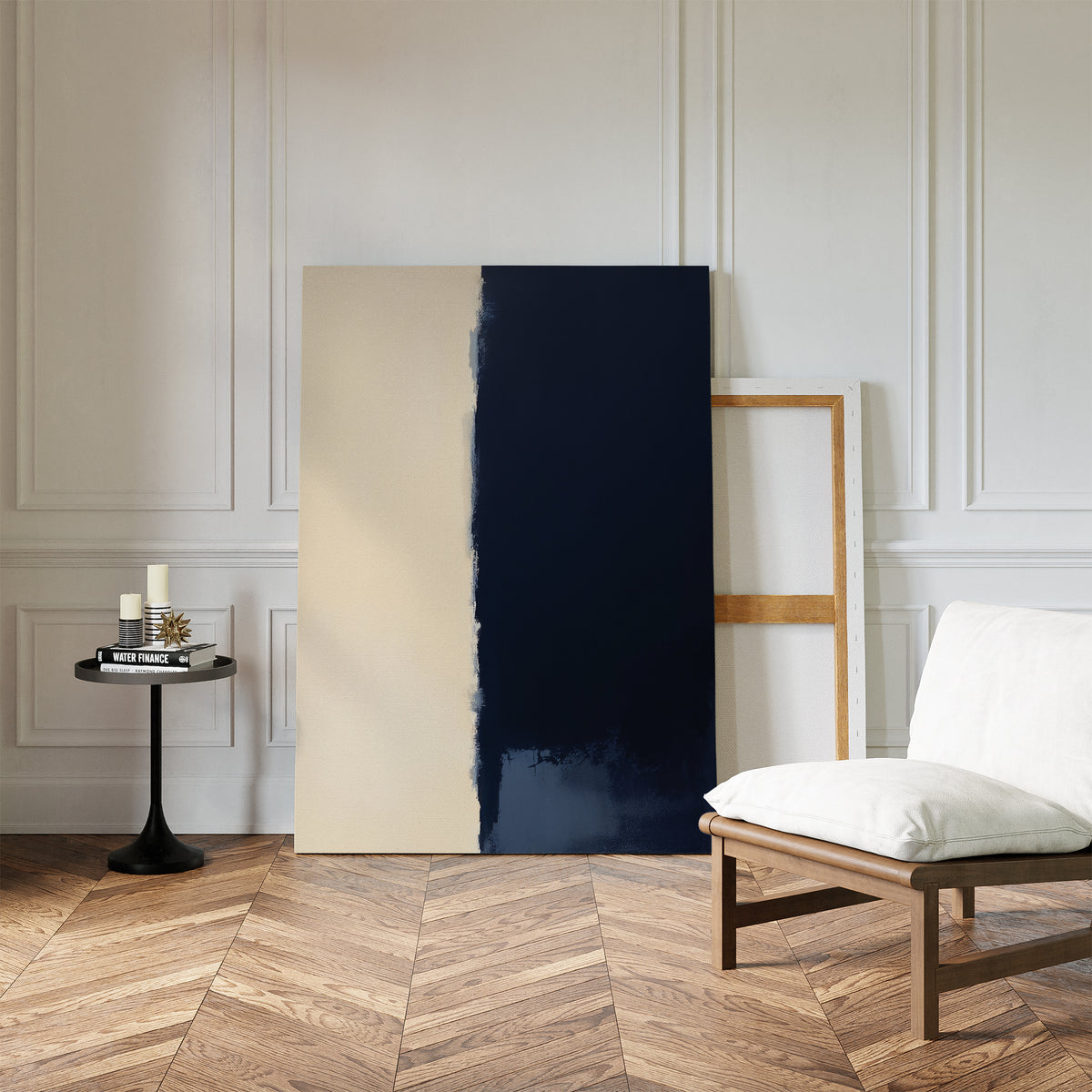 A modern room with herringbone wood floors, a white cushioned chair, a small black side table with candles and books, and the Navy Division Canvas Art - Vertical leaning against a white paneled wall creates an air of modern elegance.