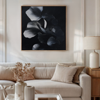 A stylish living room features a beige sofa with neutral cushions, a matching lamp and side table, dried flowers in a vase, and the Nocturnal Bloom Abstract Canvas Art displayed above the sofa.
