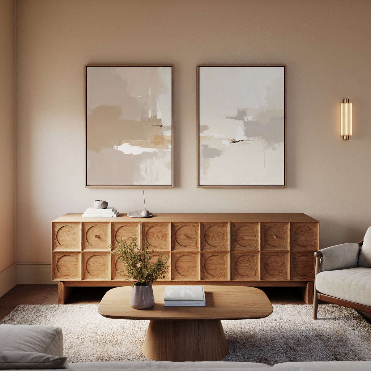 A modern living room with contemporary elegance features Neutral Territory - Set Of 2 neutral-colored furniture, a wooden coffee table, a textured sideboard, minimalist artwork, a wall sconce, greenery in a vase, and a light rug.