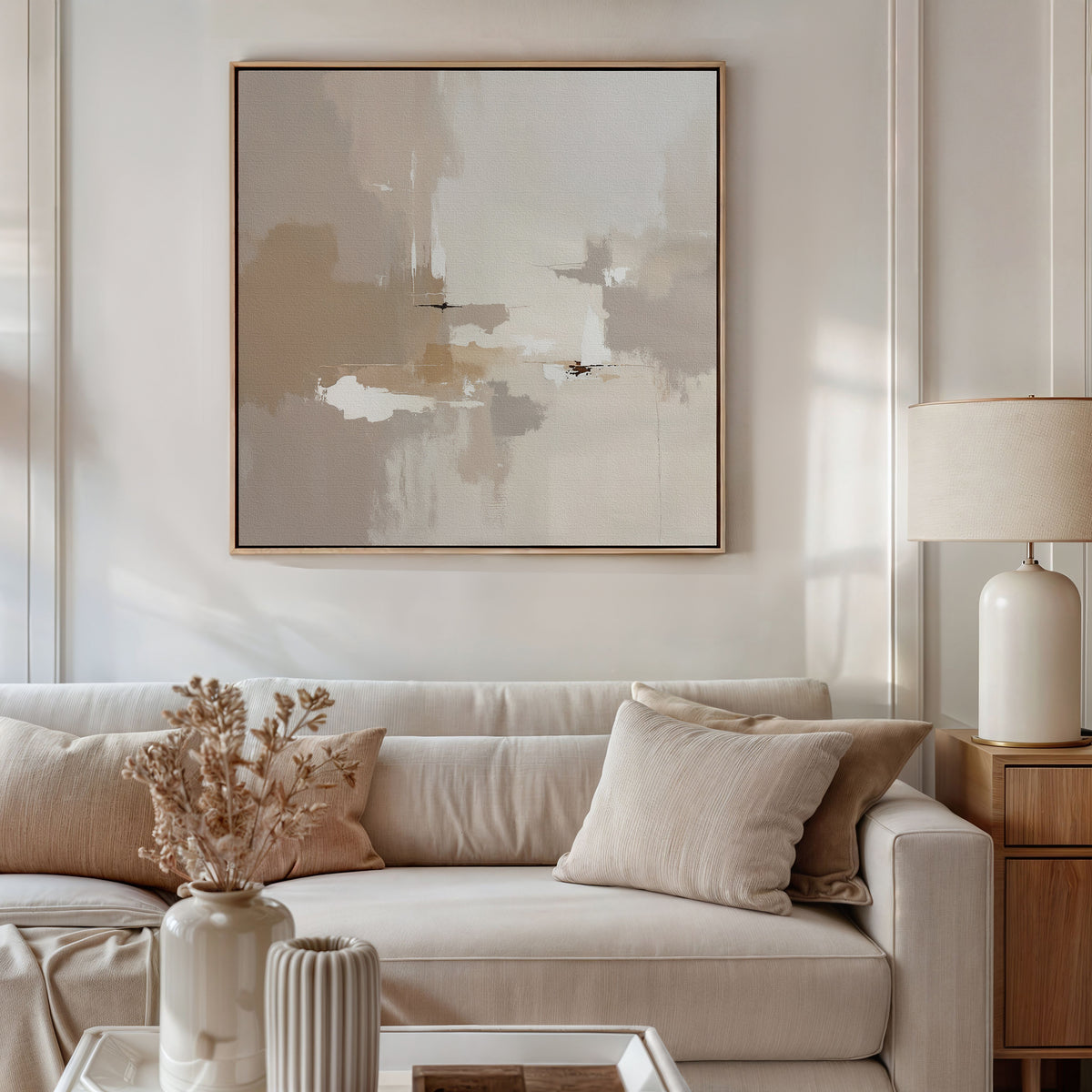 A modern living room featuring a light beige sofa, neutral cushions, a table lamp, dried flowers in a vase, and the Neutral Territory Canvas Art - Square above the sofa for a touch of contemporary elegance.