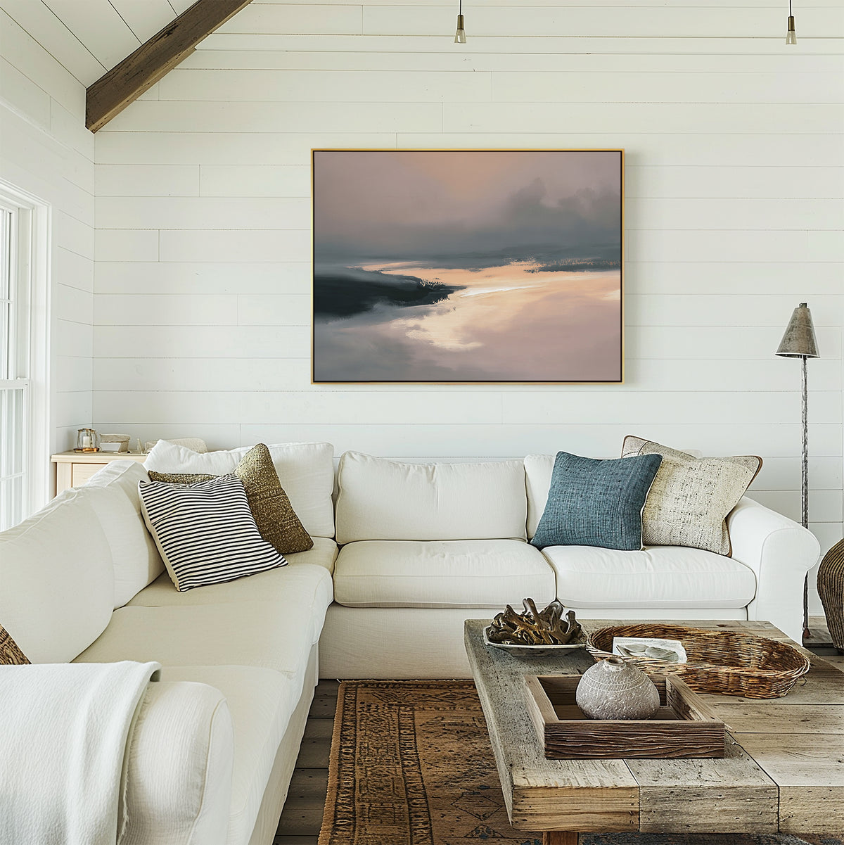 A cozy living room with a white sectional sofa, assorted pillows, a rustic wooden coffee table, and the Nordic Fjord Canvas Art - Horizontal on a white shiplap wall. Natural light streams in through a nearby window.