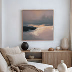 A modern, minimalist living room features a beige sofa, neutral cushions, wood sideboard with stacked books and decorative vases, and the Nordic Fjord Canvas Art - Square in soft earth tones as the focal wall décor.