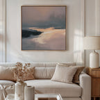 A modern living room with a beige sofa, matching cushions, a side table with a white lamp, dried flowers in a vase, and the Nordic Fjord Canvas Art - Square in muted tones hanging above the sofa.