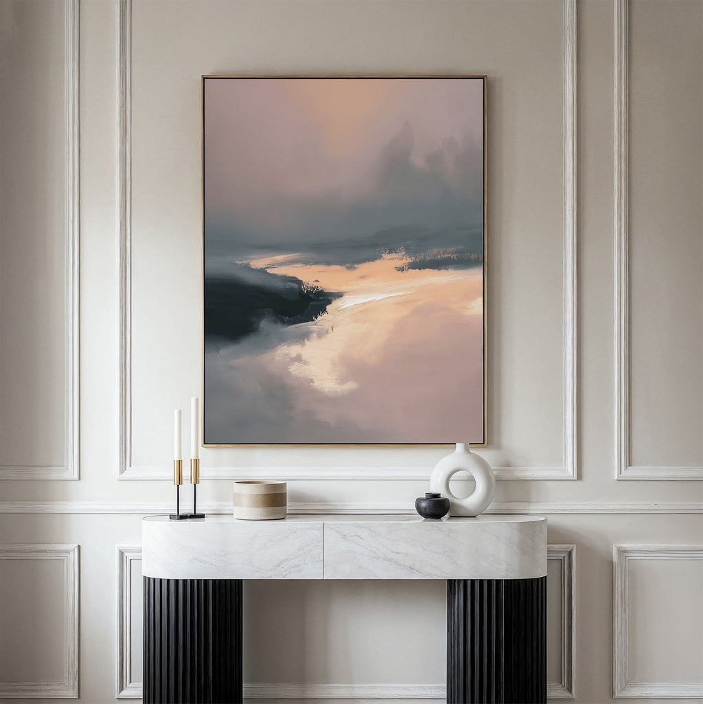A minimalist console table with decorative items stands against a beige wall, topped by the Nordic Fjord Canvas Art - Vertical featuring a misty landscape in soft peach, black, and blue tones.