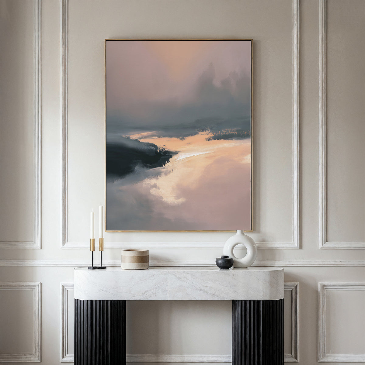 A minimalist console table with decorative items stands against a beige wall, topped by the Nordic Fjord Canvas Art - Vertical featuring a misty landscape in soft peach, black, and blue tones.