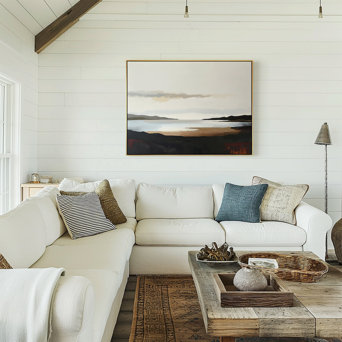A cozy, modern living room features a white sectional sofa with throw pillows, a rustic wooden coffee table, and the Nordic Waters Canvas Art - Horizontal displayed on a white shiplap wall as natural light streams in from the left.