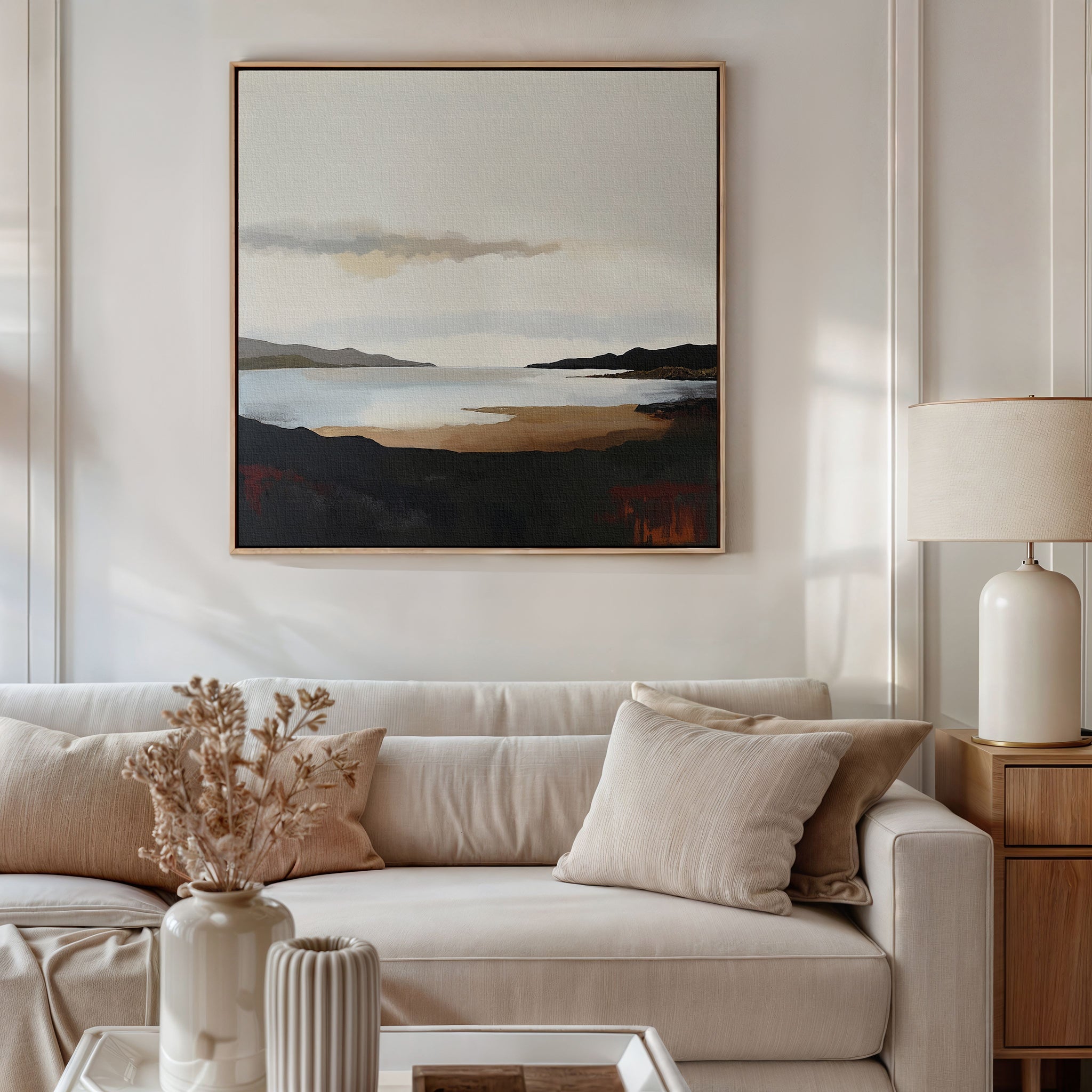 A modern living room features a beige sofa with neutral pillows, a vase of dried flowers on the table, and the Nordic Waters Canvas Art - Square hanging above the sofa for a serene touch. A lamp rests on a wooden side table.