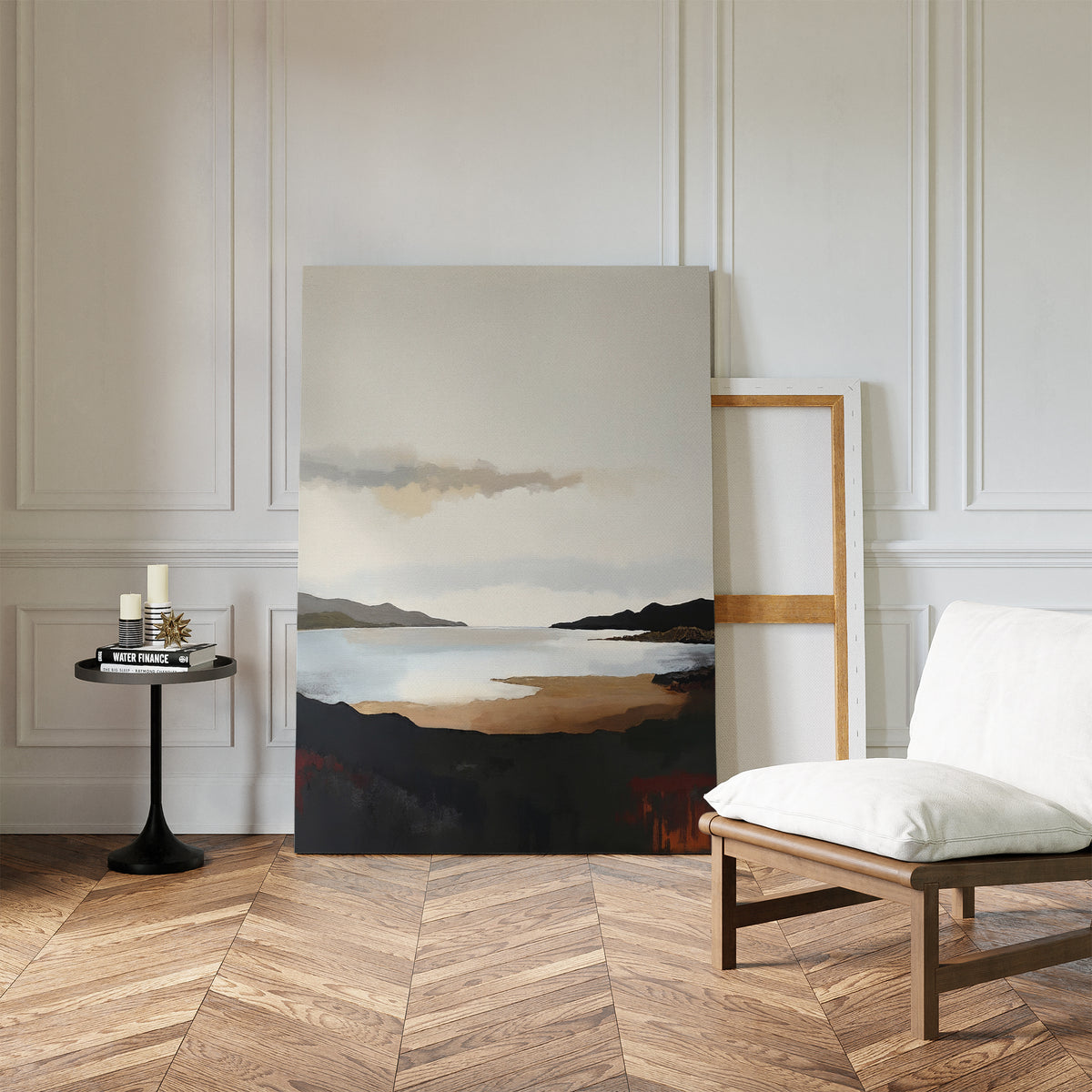 A minimalist room with herringbone wood floors, a white cushioned chair, a round black side table with candles and books, and calming wall art featuring the Nordic Waters Canvas Art - Vertical resting against a white paneled wall.