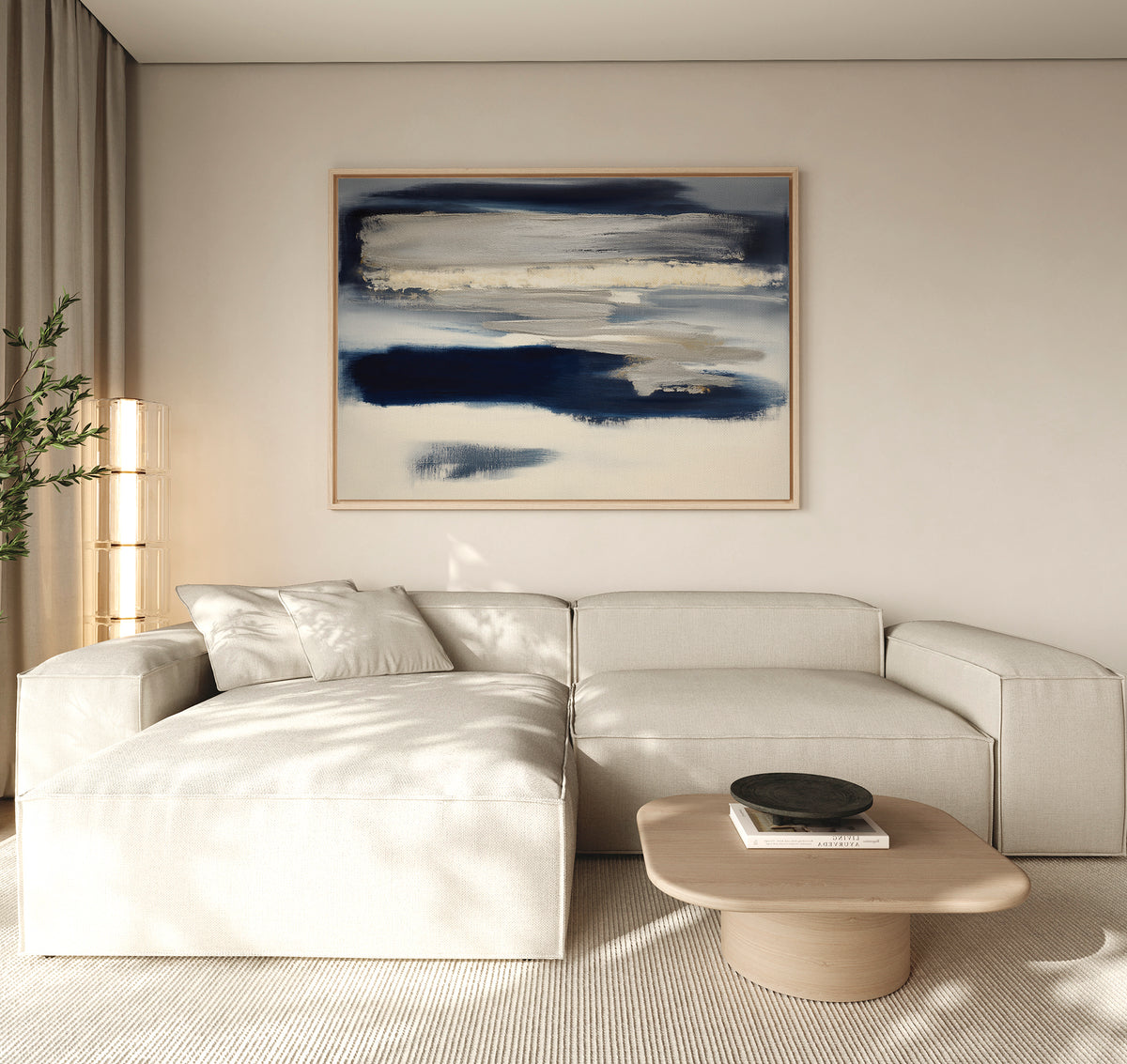 A modern living room with a light beige sectional, wooden coffee table, tall plant, and the Northern Tides Canvas Art - Horizontal in blue and white tones. Natural light highlights the minimalist décor.