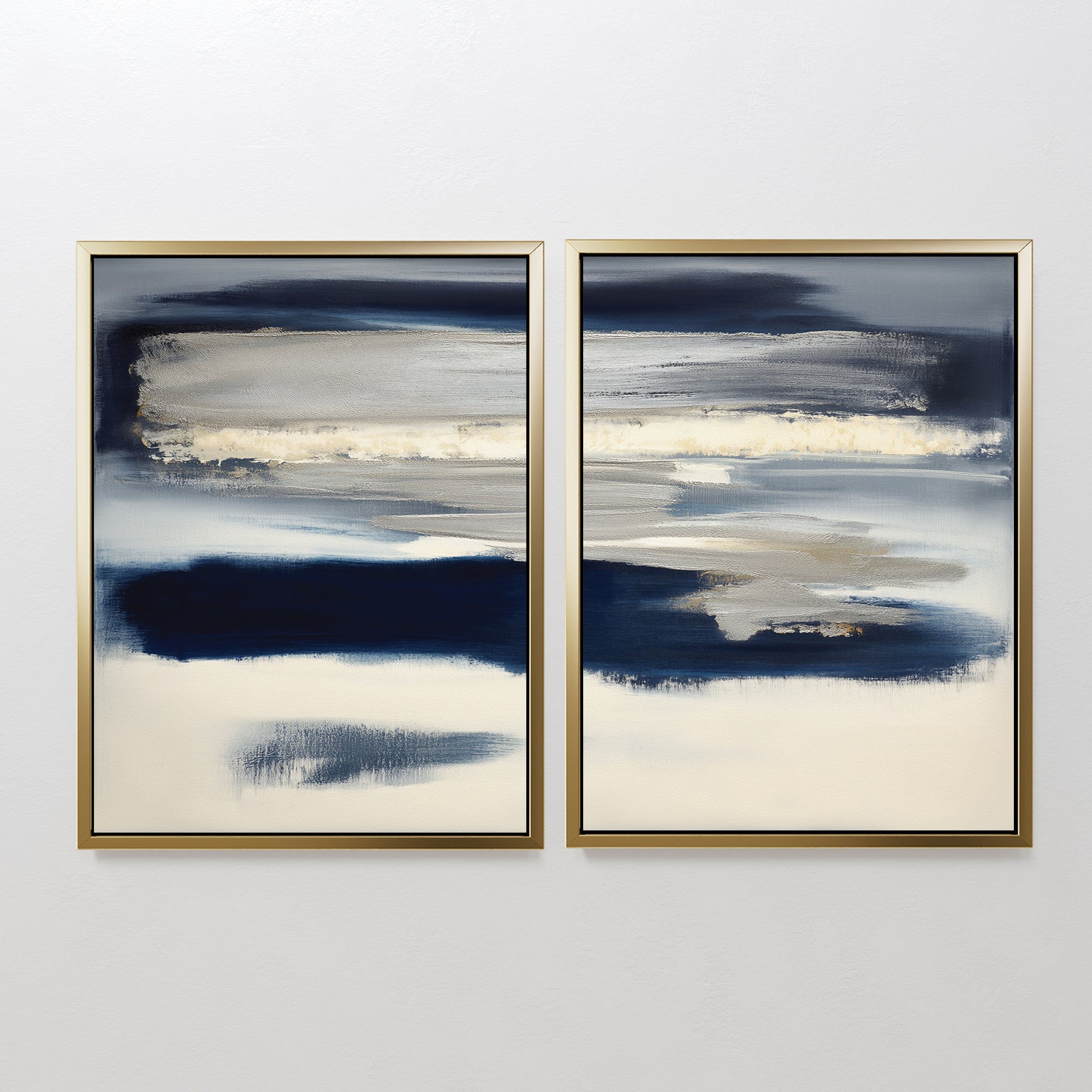 Northern Tides - Set Of 2 features abstract prints with horizontal navy, gray, beige, and white brushstrokes in minimalist style, each framed in slim gold frames and displayed side by side against a plain white wall.