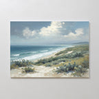 The Ocean Bluff Canvas Art - Horizontal features a serene coastal scene with waves on a sandy beach, blue ocean, cloudy sky, and green shrubs—a beautiful seaside artwork.