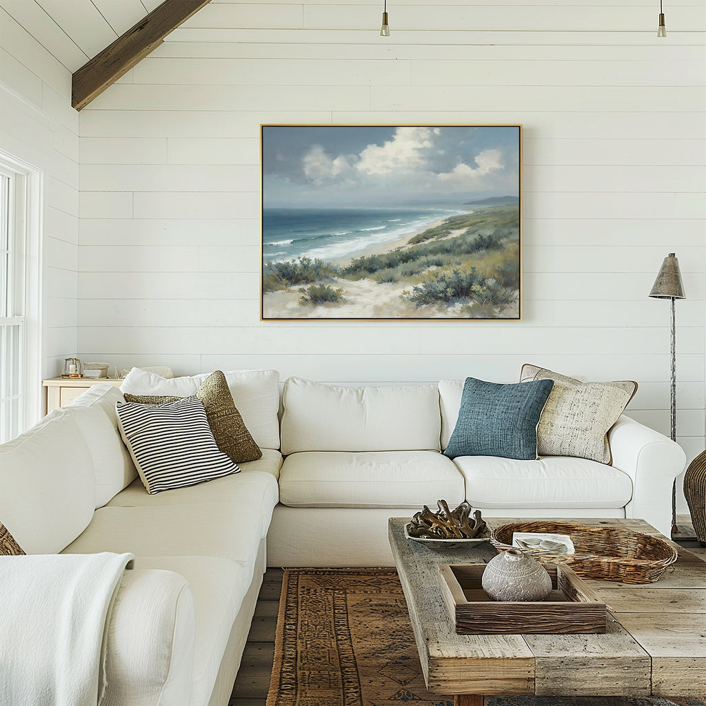A bright, cozy living room with white shiplap walls, a large white sectional sofa with cushions, a rustic wooden coffee table, and the Ocean Bluff Canvas Art - Horizontal hanging above the couch.