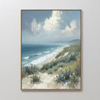 Ocean Bluff Canvas Art - Vertical showcases a sandy beach, gentle waves, grassy dunes, and a cloudy sky. Hung on a white wall, this serene artwork captures the peaceful essence of a Nordic Park coastal landscape.