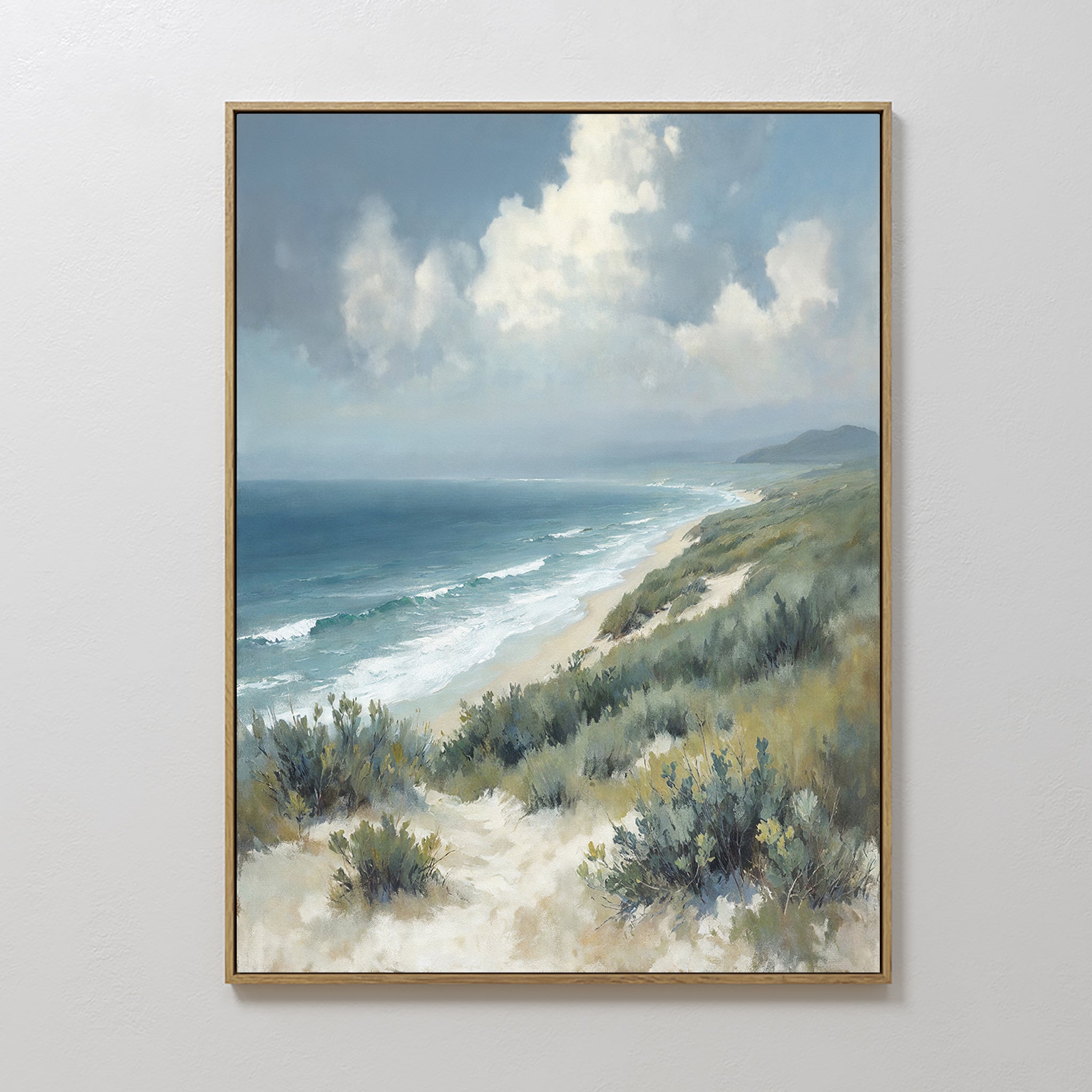 Ocean Bluff Canvas Art - Vertical showcases a sandy beach, gentle waves, grassy dunes, and a cloudy sky. Hung on a white wall, this serene artwork captures the peaceful essence of a Nordic Park coastal landscape.