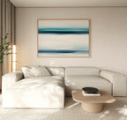 A modern living room features a light beige sectional, wooden coffee table, and the Ocean Motion Canvas Art - Horizontal. Soft natural light through beige curtains enhances the tranquil ambiance and serene sophistication of the space.