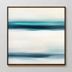 Ocean Motion Canvas Art - Square features an abstract print in a dark frame with softly blended horizontal bands of blue, teal, and white, evoking serene sophistication and a minimalist seascape against a light background.