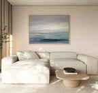Minimalist living room featuring a light beige sectional, low wooden coffee table, potted plant, and Ocean Swells Canvas Art - Horizontal. Neutral tones and soft natural light contribute to a calm atmosphere.
