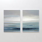 Ocean Swells - Set Of 2 features serene coastal prints with calm blue-gray waters, gentle waves, and a cloudy sky, capturing peaceful Nordic Park-inspired wall art in soft, muted tones.
