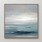 The Ocean Swells Canvas Art - Square features a framed coastal print of calm blue and gray waves under a cloudy sky, blending soft, muted tones for a tranquil, minimalist look—ideal serene wall art for any space.