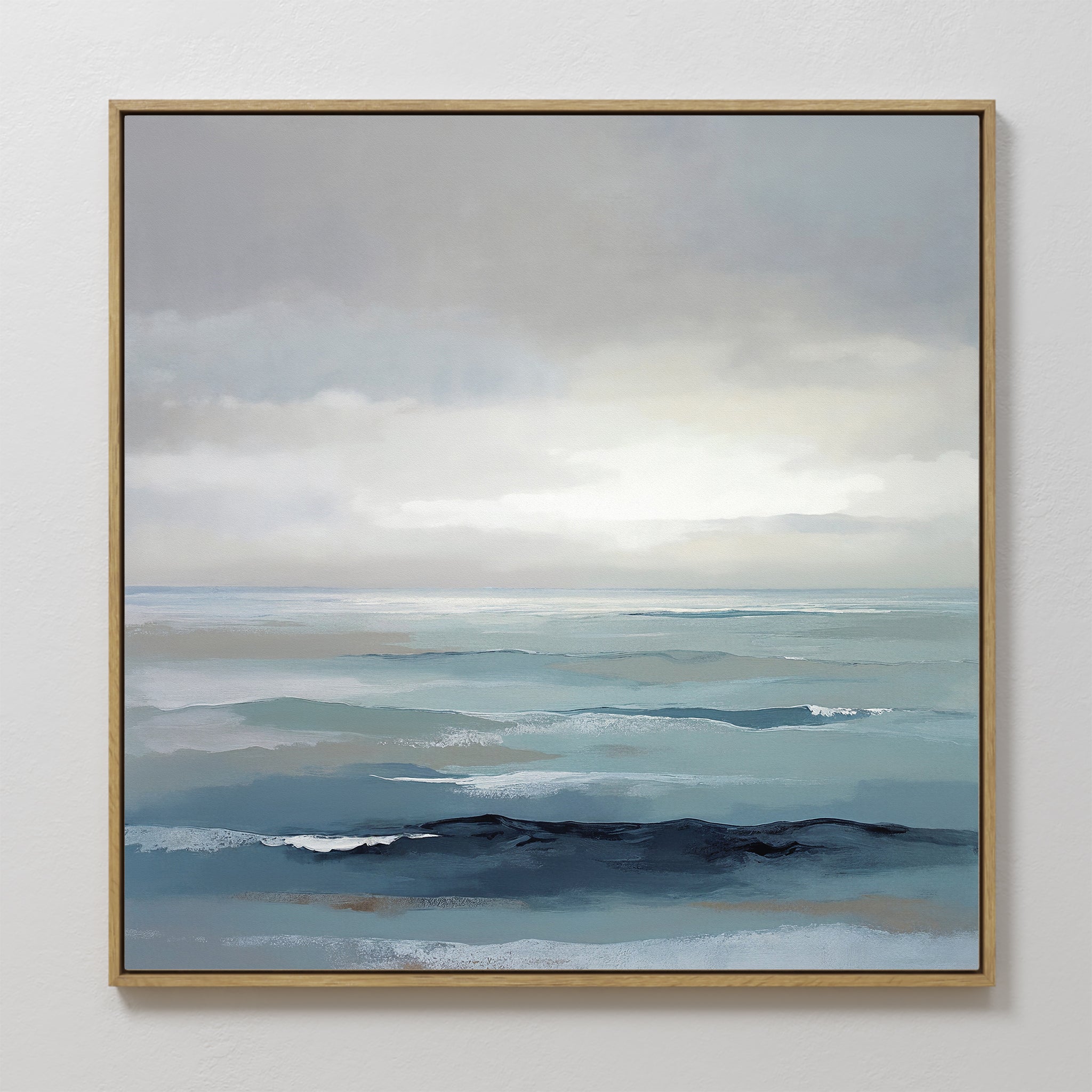 The Ocean Swells Canvas Art - Square features a framed coastal print of calm blue and gray waves under a cloudy sky, blending soft, muted tones for a tranquil, minimalist look—ideal serene wall art for any space.