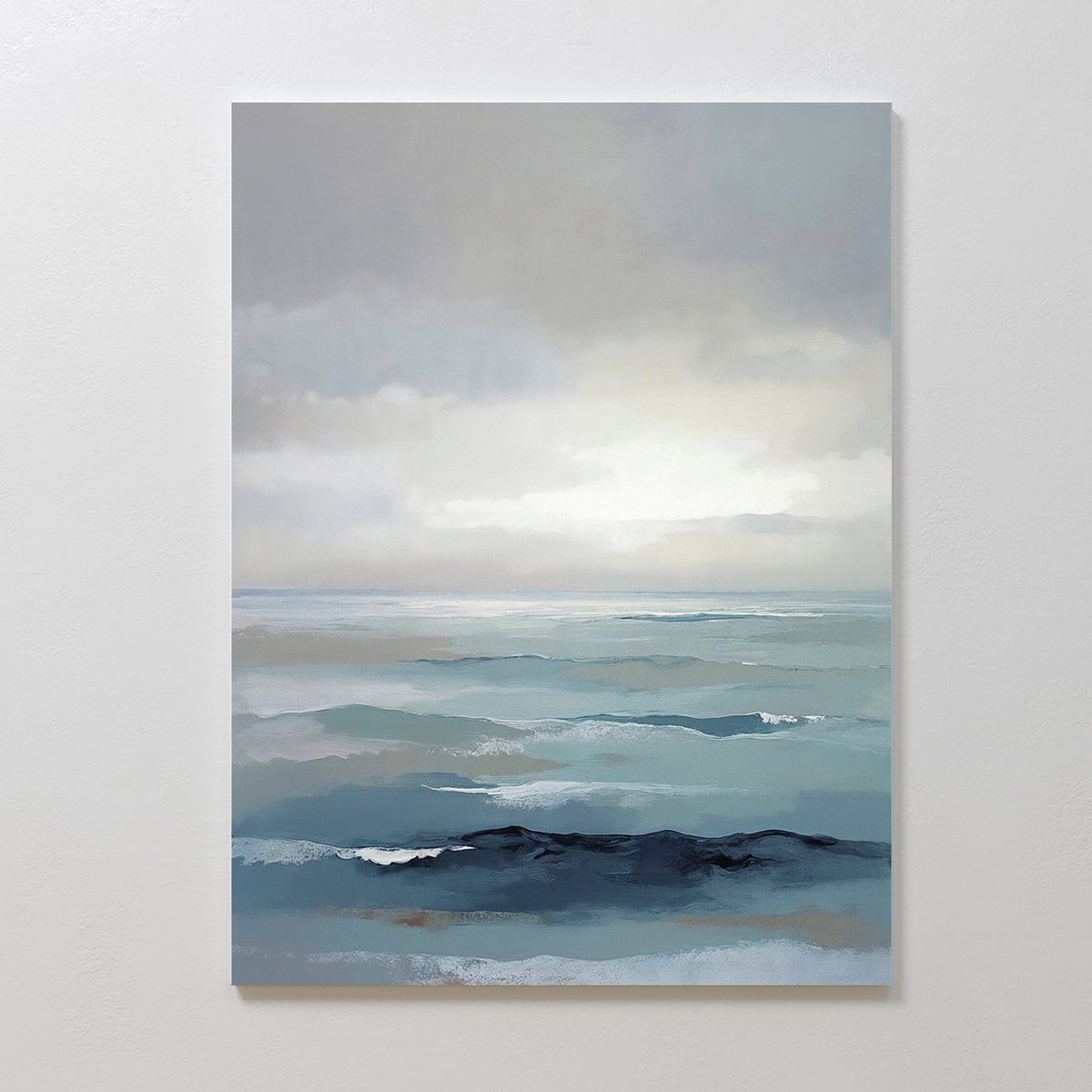 The Ocean Swells Canvas Art - Vertical features a serene seascape in soft blue, gray, and white tones with gentle waves and light breaking through clouds, beautifully displayed on a plain white wall.