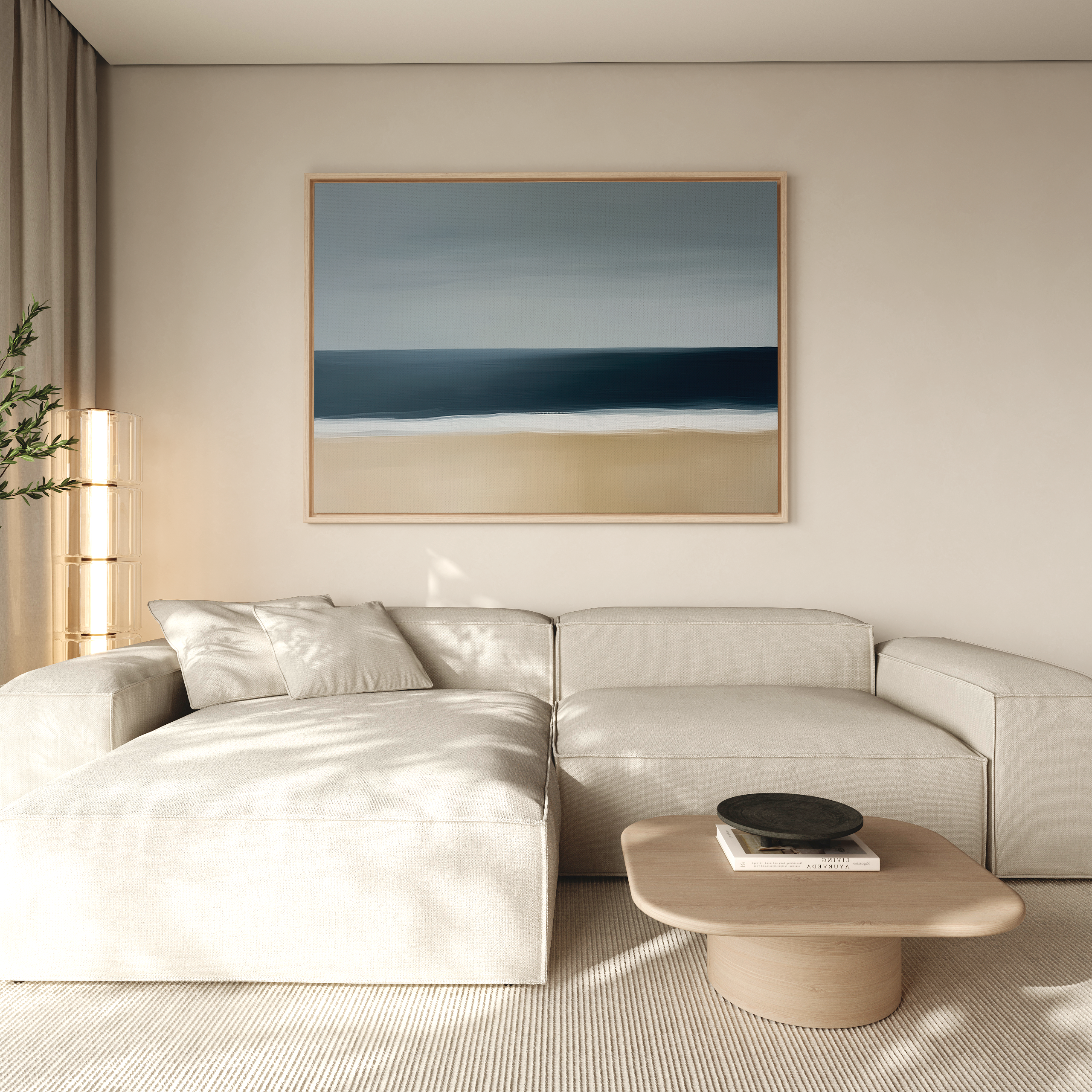 A modern living room features a light beige sectional sofa, a round wooden coffee table, and the Ocean Edge Canvas Art – Horizontal above. Soft natural light streams in from the left, with a green plant partially visible.