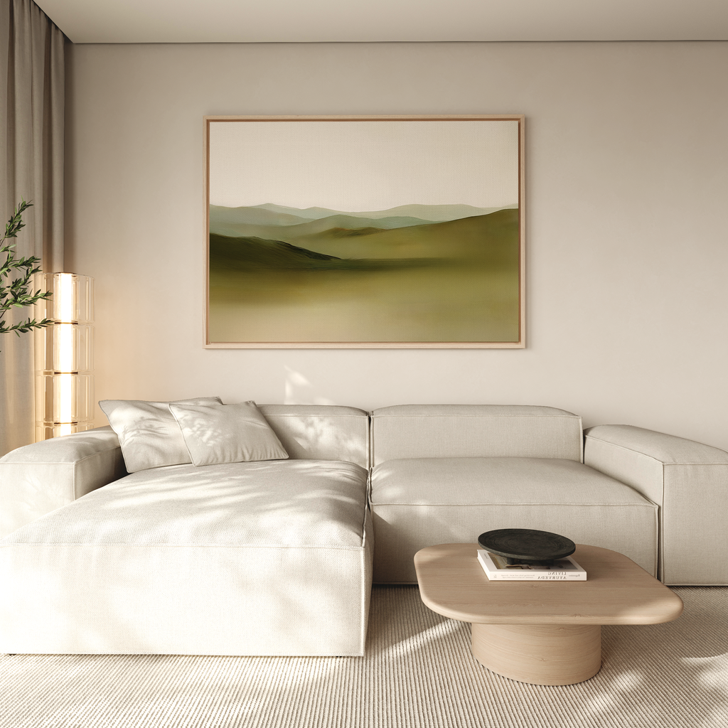A modern living room with a light beige sectional sofa, a wooden coffee table with a black bowl, and the Pastoral Peace Canvas Art depicting green hills on the wall, decorated in neutral tones with natural light streaming in.