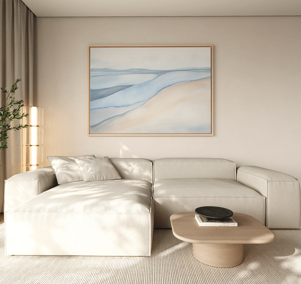 A modern living room features a light beige sectional, low wooden coffee table, tall floor lamp, and calming artwork—a large Pale Currents Canvas Art - Horizontal in blue and beige tones—evoking the serene spirit of Nordic Park.