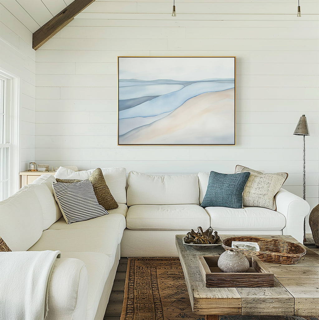 Cozy living room with a white sectional sofa, neutral and blue pillows, a rustic wooden coffee table, and the Pale Currents Canvas Art - Horizontal on a white shiplap wall. Natural light fills the serene space.